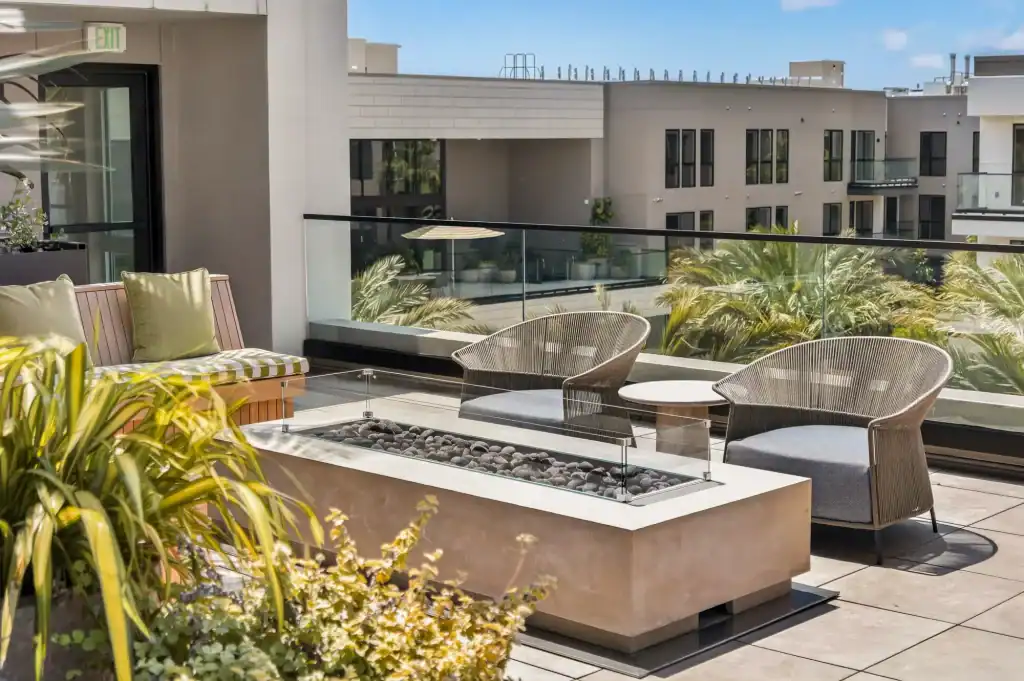 Modern rooftop patio with seating and fire feature overlooking cityscape.