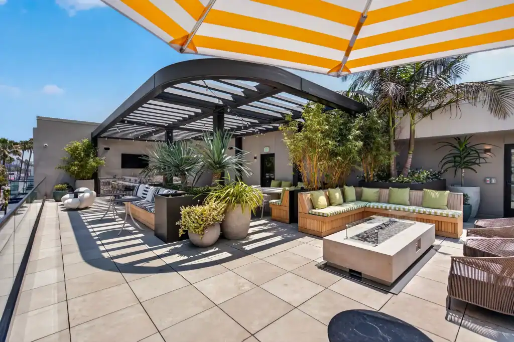 Rooftop terrace featuring contemporary outdoor furniture, potted plants, and a vibrant yellow-stripe.