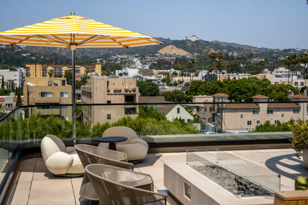 Bright rooftop terrace with sunset view over city skyline and hills in the background.