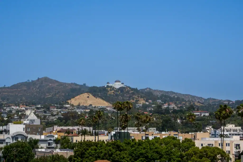 Scenic view of 5420 Sunset with cityscape and hills in the background during sunset.