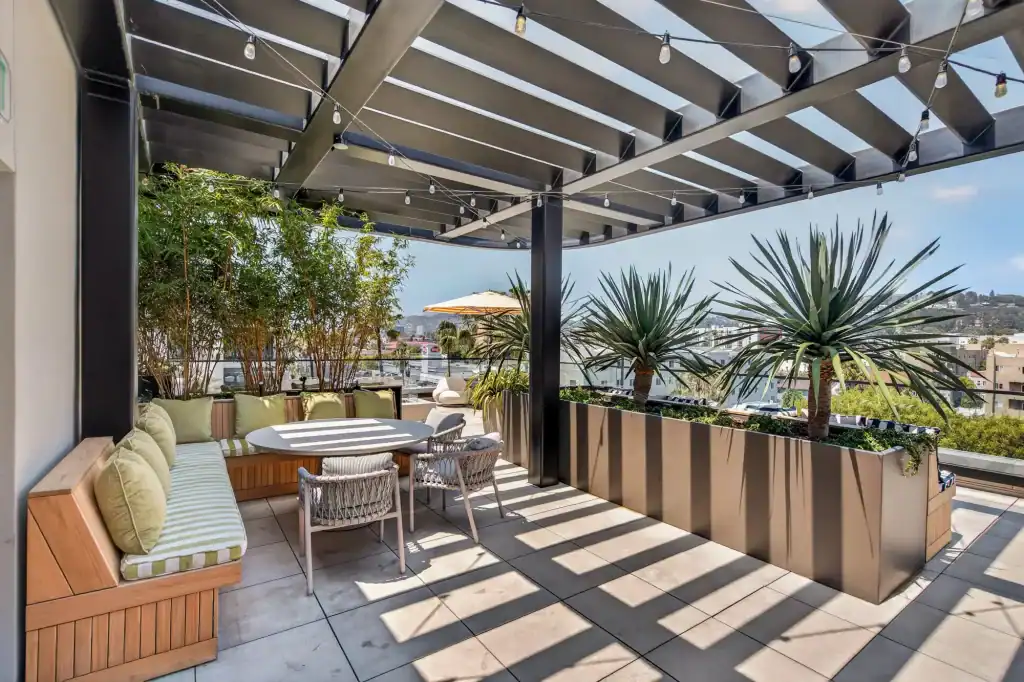 Rooftop terrace featuring comfortable outdoor seating, potted plants, and string lights under a perg.